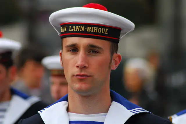 Marin dans le port de Brest en bretagne avec un pompom rouge